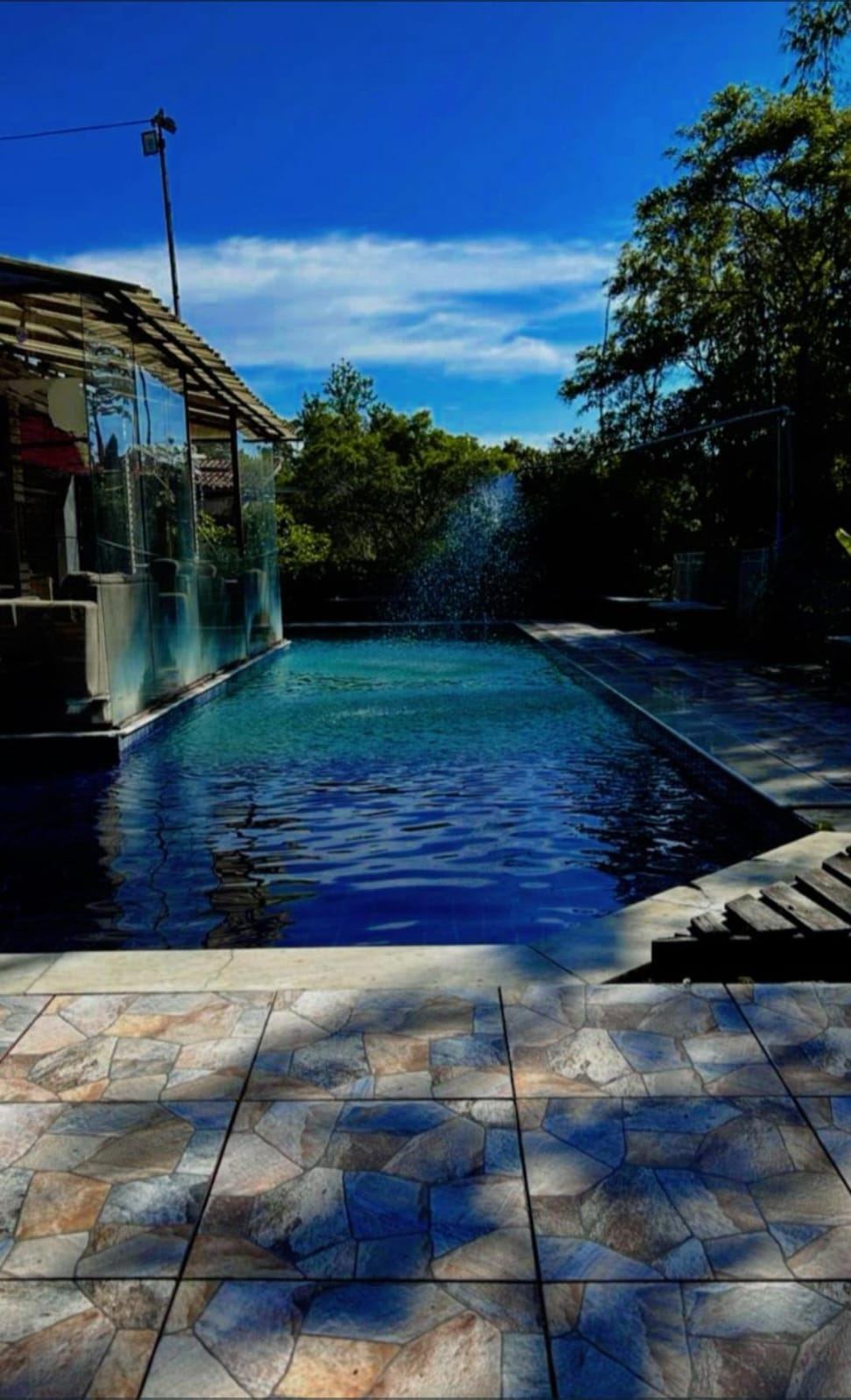 Piscina com cascata e deck de pedras
